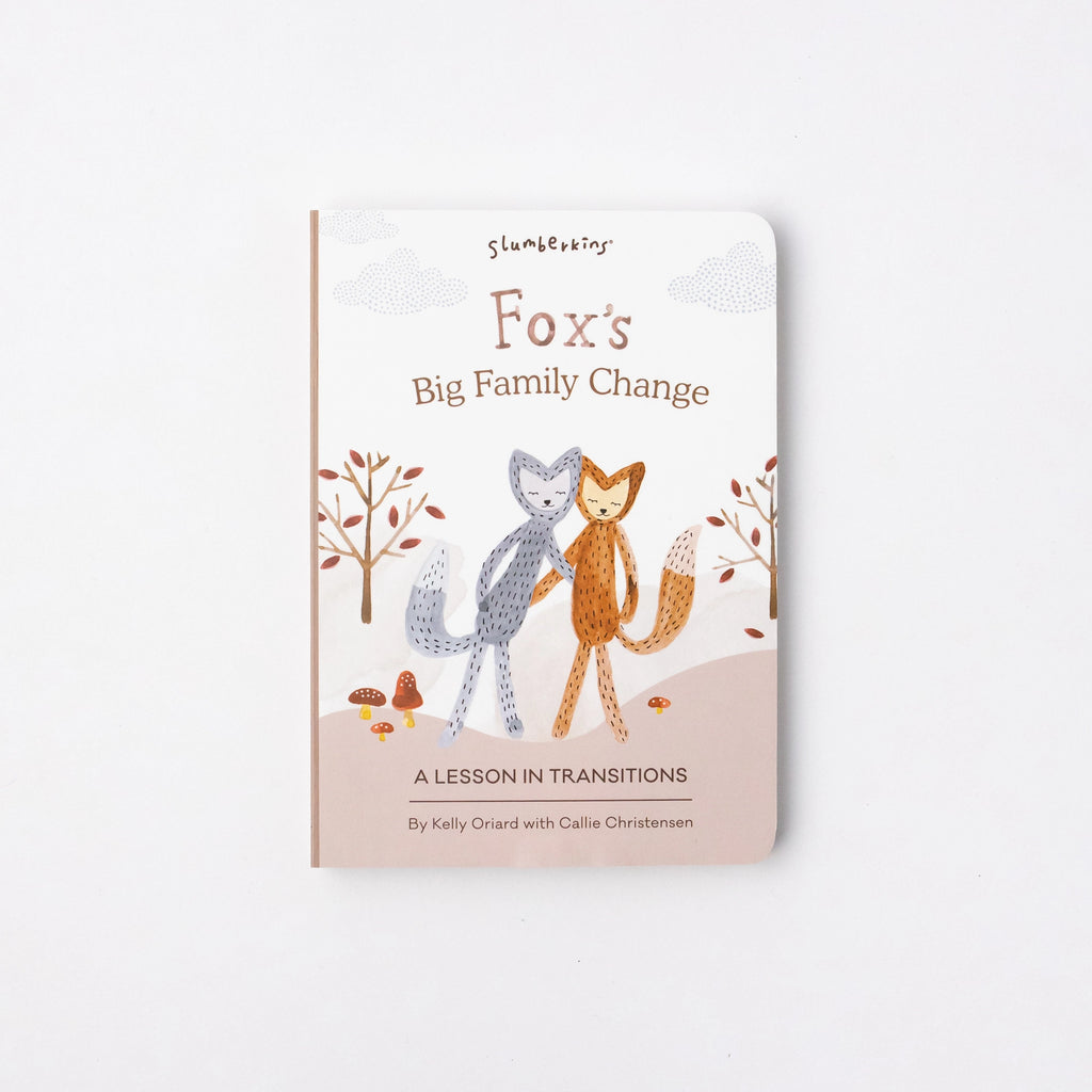 A Slumberkins Fox Kin + Lesson Book On Family Change with an illustration of two fox figures, one grey and one orange, standing among trees and leaves. It's subtitled "a lesson in anxiety support.