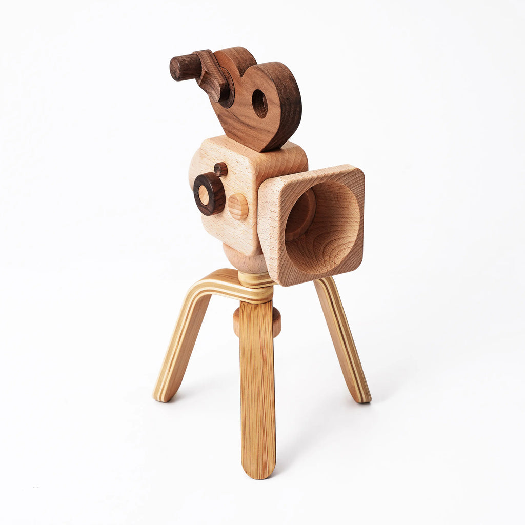 The Father’s Factory | Super 16 Pro Wooden Toy Camera with Tripod features three tripod legs, a lens, geometric wood shapes, and a kaleidoscope viewfinder—perfect for pretend play and shown on a plain white background.