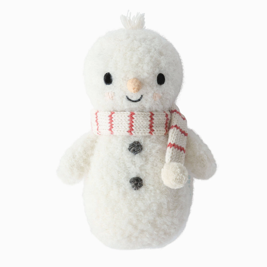 The Cuddle + Kind Baby Snowman - Candy Cane is a soft plush toy made from Peruvian alpaca yarn, featuring black button eyes, a carrot nose, and a red-and-white striped scarf—ideal for collectible stuffed animal enthusiasts.