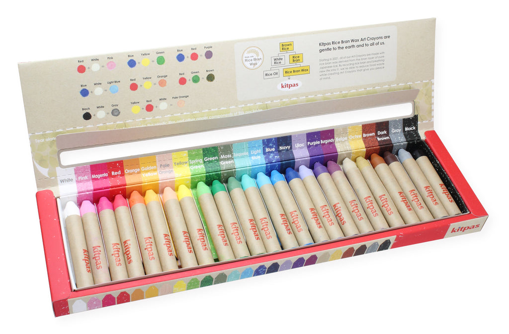 The Kitpas Crayons - 24 Colors, crafted with rice bran wax in Japan, are arranged in a neat row in an open box. Each crayon features a beige paper wrapper, while the red cardboard lid displays the color range with labeled swatches. This elegant packaging holds a premium selection of vibrant art supplies.