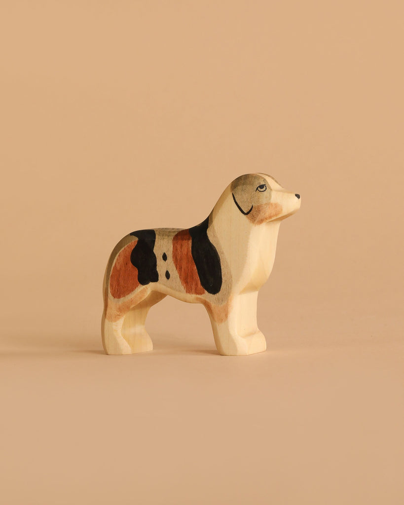 The Handmade Holzwald Australian Shepherd is a small, hand-painted wooden toy dog with brown, black, and white markings—perfect for imaginative play or as a charming, sustainable addition to any toy collection.