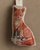 The Coral & Tusk Fox Tree Trimmer Ornament is a small, fabric Christmas ornament shaped like a fox, featuring detailed orange, white, black, and gold embroidery to illustrate its fur.