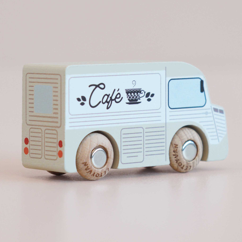 No. 11 GT65 Coco | Made in England—a wooden coffee van painted white and blue with “Café” and a cup design on its side, featuring wooden wheels and simple line details, set against a plain light background—perfect for imaginative storytelling or thoughtful gifting.