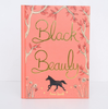 The "Black Beauty | Collector's Edition | Hardcover" has a coral-pink cover with gold cursive lettering, illustrated tree branches, flowers, and a small black horse at the bottom.
