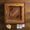 The Monopoly Luxury Edition, in brown and gold, is displayed on a wooden table with cards, die-cast metal tokens, paper money, and property cards neatly arranged for a premium board game experience.