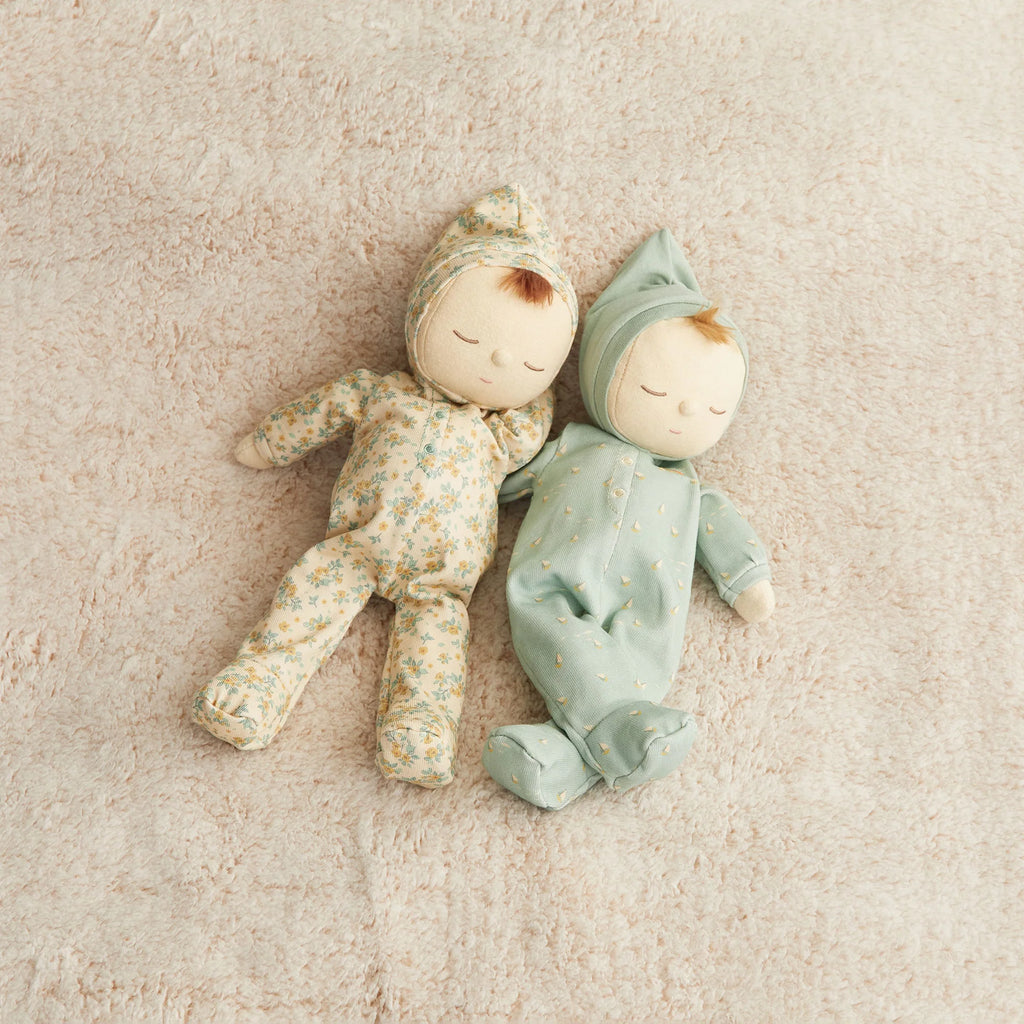 Two soft Olli Ella Dozy Dinkum - Pickle Blossom dolls lie side by side on a light beige textured surface, both dressed in pastel floral and polka dot onesies with matching hats and closed eyes.