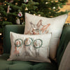 The Christmas Wreath Trio Pocket Pillow, featuring embroidered woodland animals with wreaths, sits on a green couch in front of a Christmas tree, while another pillow behind it shows woodland friends standing together.