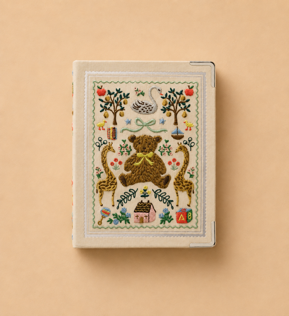 The Storybook Embroidered Small Photo Album features a beige bookcloth cover with embroidered animals, trees, a swan, flowers, and alphabet blocks in a decorative folk-art style on a plain tan background, and holds up to 48 photos.