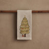 The Coral & Tusk Peek a Tree Tea Towel, in beige linen, hangs on a wooden rod and features an embroidered woodland Christmas tree with ornaments, a shining star, and tiny wrapped gifts—an ideal touch of holiday cheer.