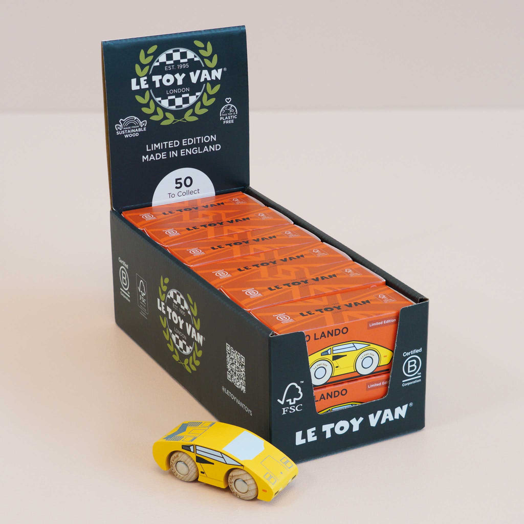 A yellow No. 14 GT80 Lando racing toy car is displayed in front of a black box containing multiple orange-packaged No. 14 GT80 Lando cars labeled “Made in England.” Each wooden supercar features a child-safe finish, ensuring hours of safe and imaginative play.