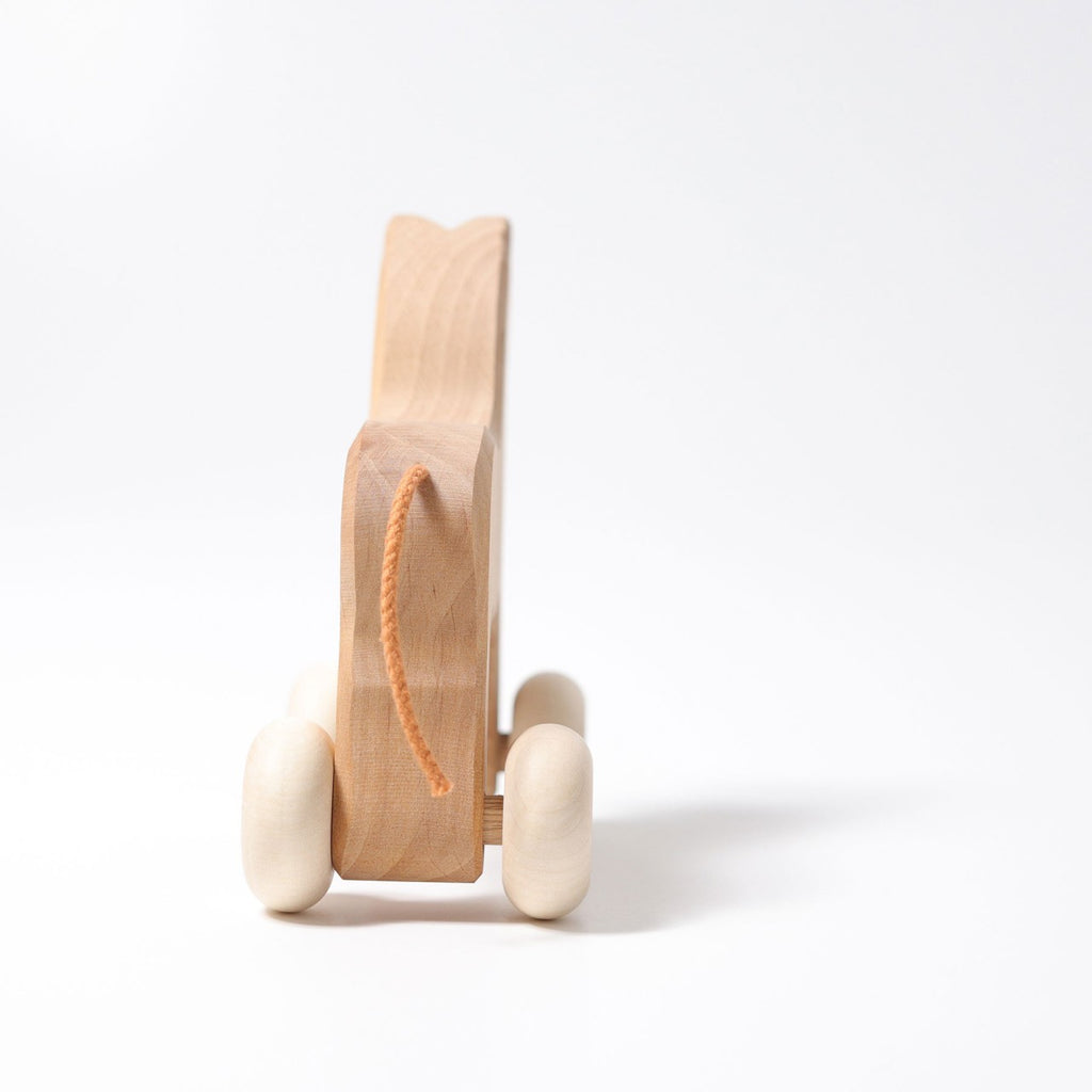 A Grimm's Wooden Horse Willy Push Toy with white wheels and an orange string is set against a plain white background, viewed from the front. Made in Germany, its clean design and natural wood grain give it a simple yet charming appearance, while ensuring it's non-toxic for safe play.