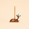 The Deer Cake Topper - Final Sale (ships in one week) is a brown ceramic deer with gold accents and a blue striped party hat, holding a lit beige candle on its back against a plain beige background.