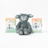 A plush gray Slumberkins Ibex Kin, a perfect children's companion, sits between two illustrated children's books titled "ibex feels deeply" and "ibex," against a plain white background.