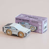A wooden toy car designed with a futuristic aesthetic is displayed next to a purple box labeled “No. 23 GT130 Dexter | Pre order Aug 2026,” featuring matching car illustrations and various icons, making it the ideal modern toy for imaginative play.