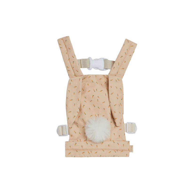 A peach-colored Olli Ella x Odin Parker Dinkum Dolls Cottontail Carrier – Hopscotch with a fluffy white pom-pom, zigzag stripe design, and adjustable shoulder straps from Olli Ella x Odin Parker, displayed on a plain black background.