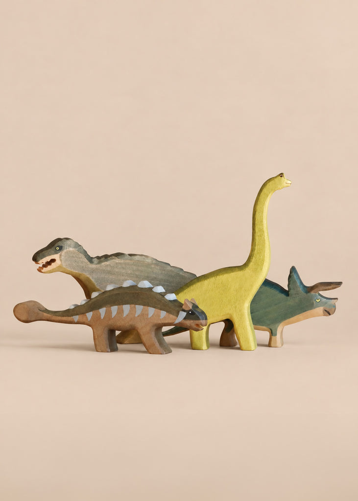 Handmade Holzwald Dinosaur Set featuring four wooden toys: a long-necked sauropod, a stegosaur, an ankylosaur, and a triceratops.
