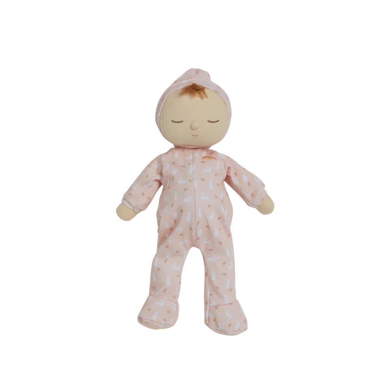 A Olli Ella x Odin Parker Dozy Dinkums - Blossom doll with a serene expression, wearing a pink floral jumpsuit made from 100% organic cotton, isolated on a black background. The doll is standing upright with its arms