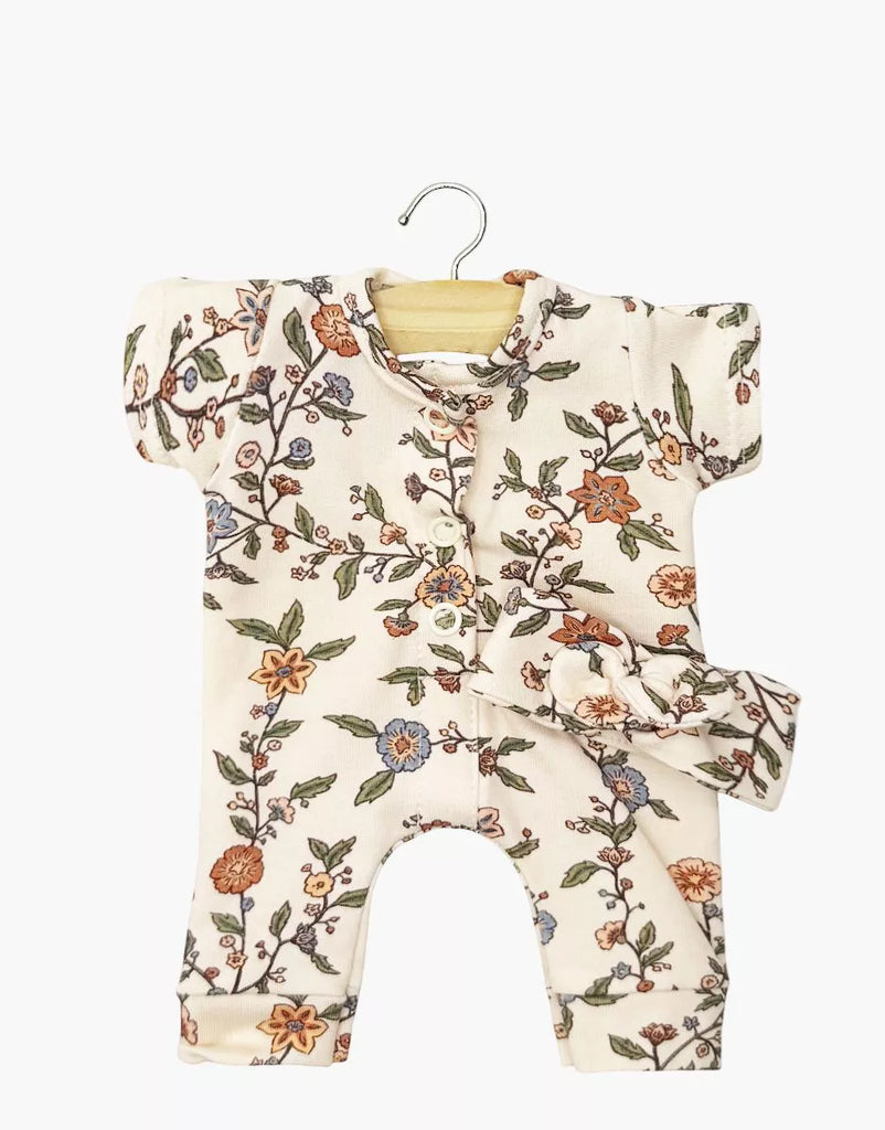 The Minikane 11" Doll Clothing set includes the Lili Jumpsuit & Headband in Jersey - Gisele, featuring a floral-patterned romper with pink, orange, and blue flowers and matching headband. Made in France.