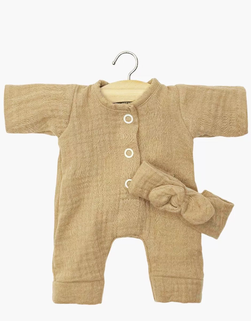 The Minikane 11" Doll Clothing set features the Lili Jumpsuit & Headband in Latte cotton gauze, displayed on a wooden hanger with the matching bow headband across the front, all set against a plain white background.