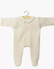 The Minikane 11" Doll Clothing | Sleep Well Corentin Onesie in Ribbed Knit - Linen is a cream ribbed cotton knit onesie with long sleeves, footed legs, and Peter Pan collar, shown on a wooden hanger against a white background. Made in France.