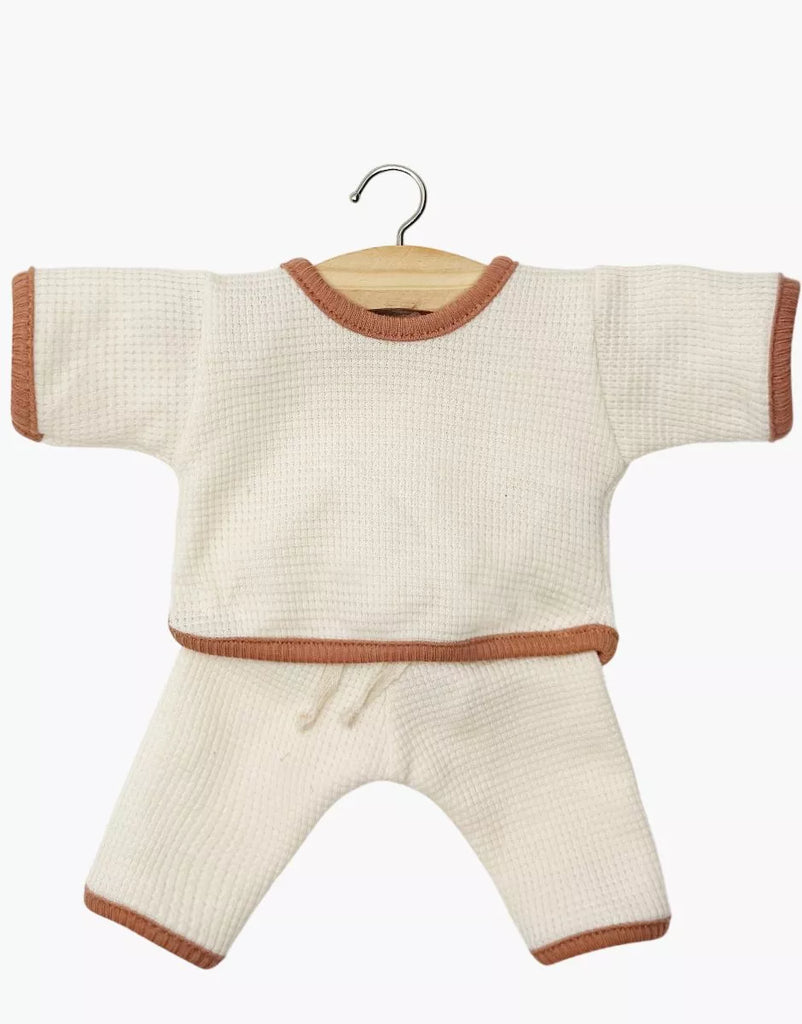 The Minikane 11" Doll Clothing Cocoon Jogger Set in honeycomb-knit ecru cotton has long sleeves and brown trim on the collar, cuffs, hem, and pant legs. Shown on a wooden hanger against a white background; fits Minikane dolls.