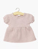 A Minikane 11" doll Faustine dress with balloon sleeves, made from orchid pink cotton gauze, hangs on a wooden hanger against a white background.