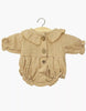 The Minikane Doll Clothing | Leonore Ruffled Romper in Cotton Gauze - Latte features long sleeves, a ruffled collar, gathered cuffs, and three wooden buttons—fits Minikane or 13 inch dolls—shown on a wooden hanger against a white background.