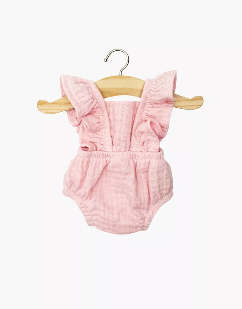 The Lou Retro Romper in Strawberry, made from cotton gauze, fits Minikane 13" dolls. This pink romper features ruffled straps and is shown hanging on a wooden hanger against a white background.