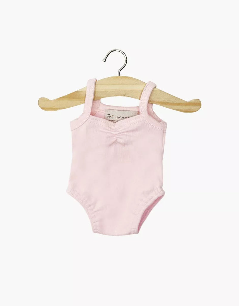 The Minikane 13" Doll Clothing | Anna Leotard in Jersey Cotton - Pale Pink is displayed on a small wooden hanger against a plain white background. This light pink leotard is designed for 13-inch dolls like Minikane.