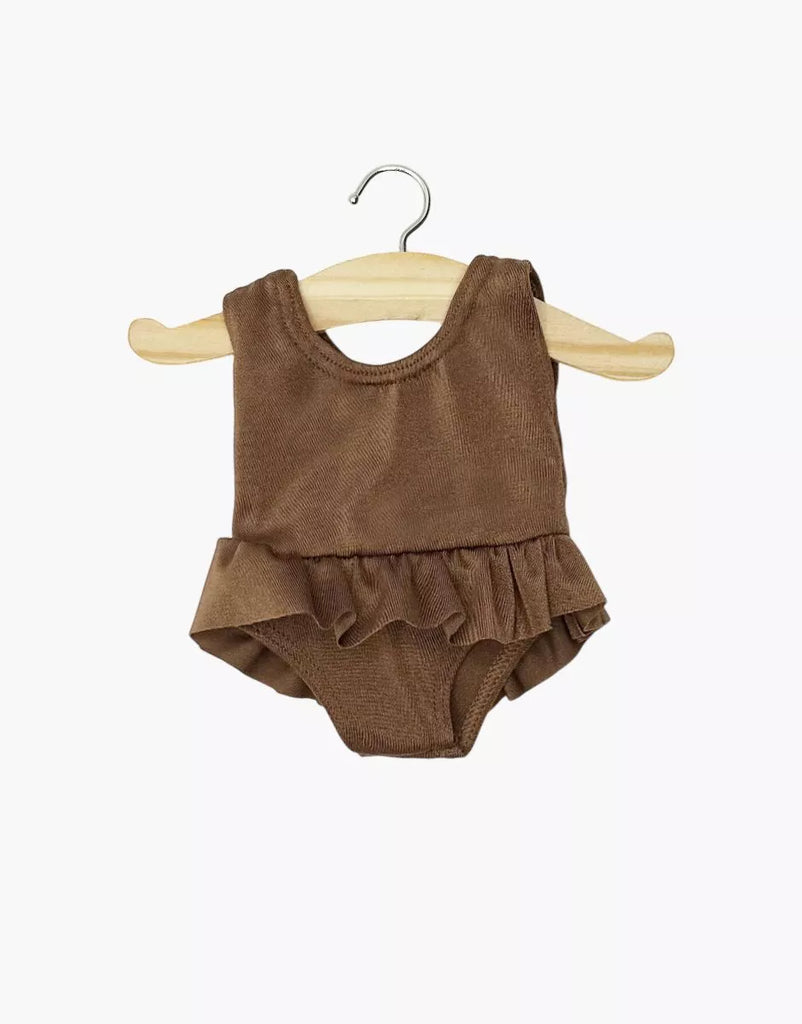 The Minikane 13" Doll Clothing Maïa Ruffled Leotard in soft lycra, chocolate brown, features a sleeveless design with waist ruffles, perfect for 13-inch dolls. Shown on a wooden hanger against a plain white background.