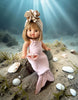 A Minikane doll wearing the 13" Mermaid Costume & Pink Pearl Seashell Set sits underwater on a rock with seashells, seaweed, and rays of sunlight—perfect for showcasing this adorable Minikane outfit.