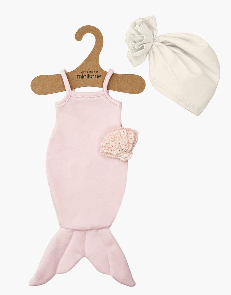 Displayed on a hanger, the Minikane 13″ Doll Clothing | Mermaid Costume & Pink Pearl Seashell Set includes a charming pink mermaid outfit featuring a matching light pink crochet top and a separate white fabric hat. Perfectly sized as 13″ and 14″ doll accessories, these whimsical Minikane doll clothes are an enchanting addition to any collection.