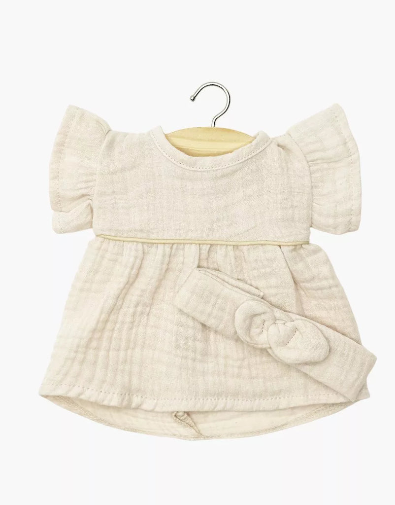 The Minikane 13" Doll Clothing | Daisy Dress & Headband in Cotton Gauze - Putty is a cream-colored outfit with short ruffled sleeves, designed for 13 inch or Minikane dolls. Shown on a wooden hanger against a white background.