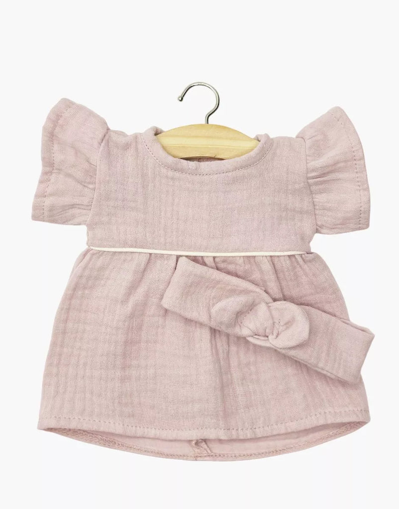 The Minikane Doll Clothing Daisy Dress & Headband in Cotton Gauze - Orchid Pink, featuring ruffled short sleeves and a gathered waist, is displayed on a wooden hanger against a white background. Perfectly sized for Minikane dolls.
