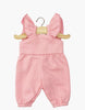 The Claudie Overalls in Cotton - Strawberry Pink for Minikane 13" dolls are displayed on a wooden hanger against a white background, featuring ruffled shoulder straps, an elastic waist, and leg openings. Perfect doll clothes for 13-inch dolls.