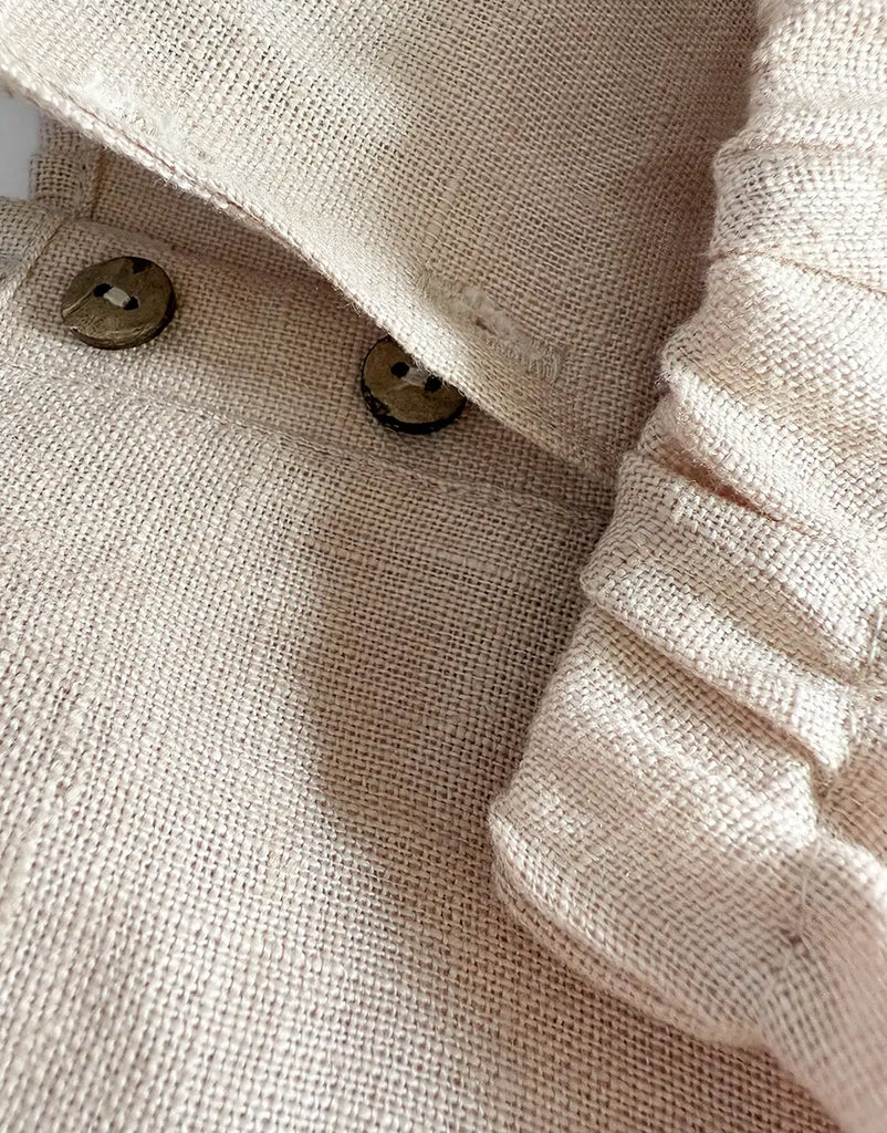 Close-up of the Minikane 13" Doll Clothing Andrea Short Set in washed linen - nude, featuring a beige textured jacket with two brown buttons and cuffed sleeves, designed for Minikane Gordis dolls.