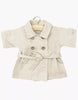 The Minikane Doll Clothing | Back to School - Tara Trench Coat in Beige Gabardine features double-breasted buttons, a tie belt, and rolled sleeves. Designed for 13" dolls, it's made in France and shown on a hanger against a white background.