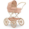 The Konges Sloejd Doll Pram - Cherry Blush features a charming vintage-style design with a pink cushioned bassinet and matching canopy. This elegant stroller is highlighted by its large beige wheels, metal frame, and quilted fabric, along with a convenient storage area beneath the padded mattress.