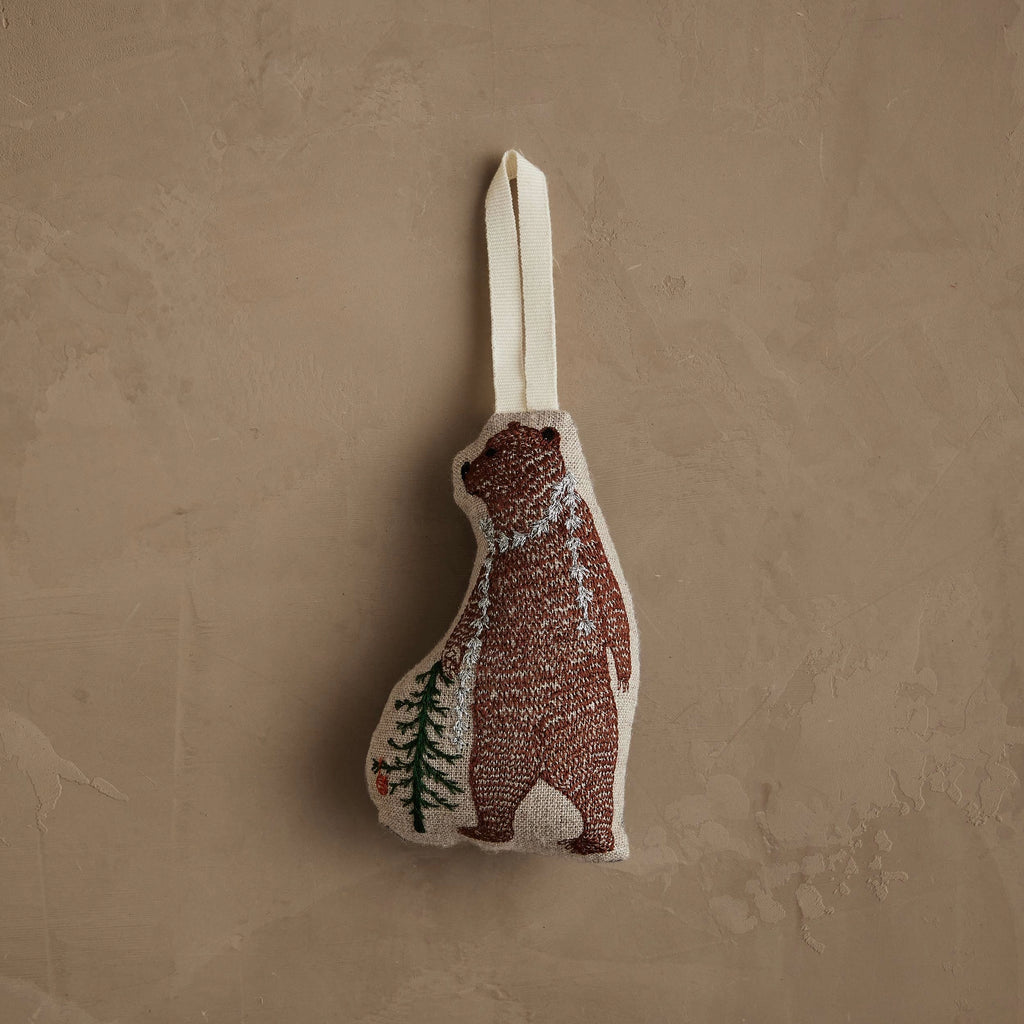 The Coral & Tusk Bear with Tinsel Ornament is a small fabric bear ornament with a cream hanging loop, simple stitched brown bear and green pine tree—ideal as a woodland Christmas decoration or mini tree ornament.