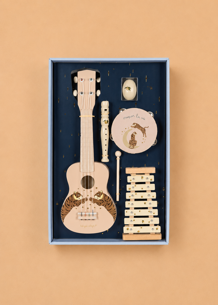 Introducing the Konges Sloejd All I Wish For Music Set - Tiger Sand: a beautifully boxed children’s set featuring a ukulele, recorder, tambourine, maracas, castanets, and xylophone—each crafted from lovely light wood tones. Arranged neatly on a dark blue background, this charming wooden instruments gift set is perfect for inspiring creativity and sparking little ones’ love of music.