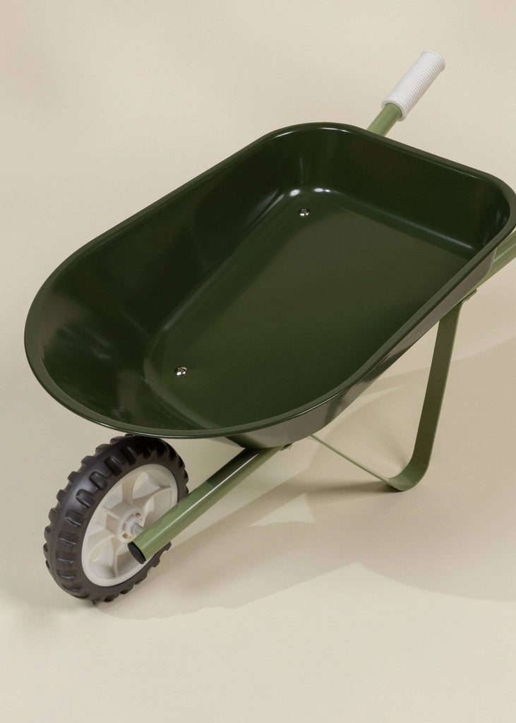 The Heritage Wheelbarrow – Liane is a green children’s wheelbarrow with a white handle and single black-and-white wheel, shown on a light-colored surface—ideal as a kids’ garden tool for outdoor fun.