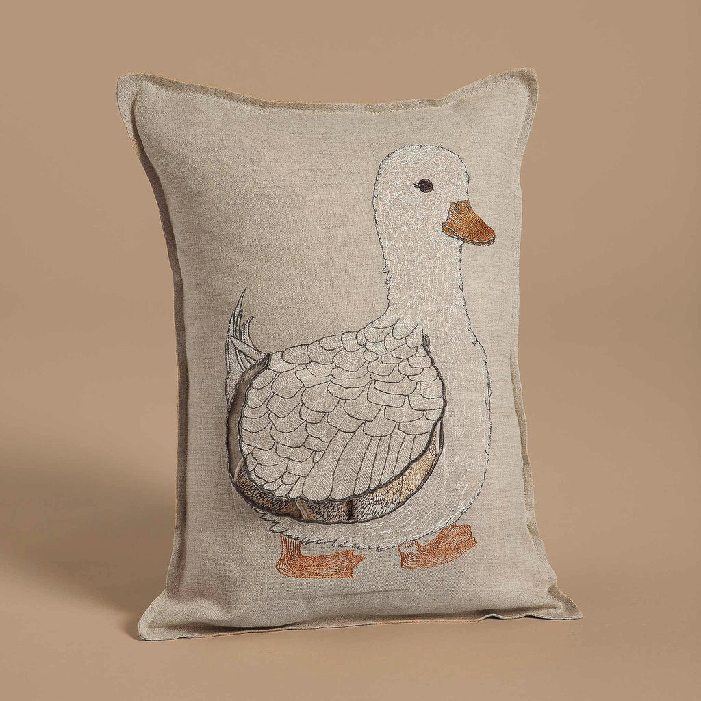 The Coral & Tusk Mama Duck Pocket Pillow features a beige design with an embroidered white duck, detailed feathers, and an orange beak and feet. Perfect for decor, its playful charm is enhanced by a matching beige background.