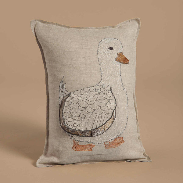 The Coral & Tusk Mama Duck Pocket Pillow features a beige design with an embroidered white duck, detailed feathers, and an orange beak and feet. Perfect for decor, its playful charm is enhanced by a matching beige background.