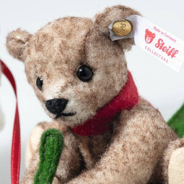 The Steiff Mama Teddy Bear With Child is a brown bear with a red scarf, gold ear button, and "Steiff Collectors" white tag. With black eyes and holding a green felt object, it's perfect for Christmas displays.