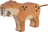 The Holztiger Saber-Toothed Tiger is a handcrafted wooden figure with painted orange fur, black spots, green eyes, long white fangs, and a short tail—lovingly made in Europe as part of the HOLZTIGER collection.