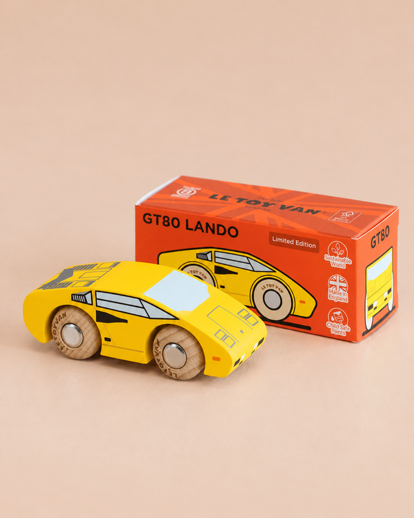 A yellow wooden supercar sits next to its orange box labeled “No. 14 GT80 Lando | Made in England.” The box features an illustration of the racing toy car and displays “Limited Edition” alongside small icons. Each piece is finished with a child-safe coating for worry-free play.