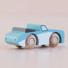 A small, light blue wooden car named “No. 1 GT10 Justin | Made in England” features natural wood wheels engraved with “LETOYVAN” and sits on a light surface, making this classic vehicle a charming keepsake for any collection.