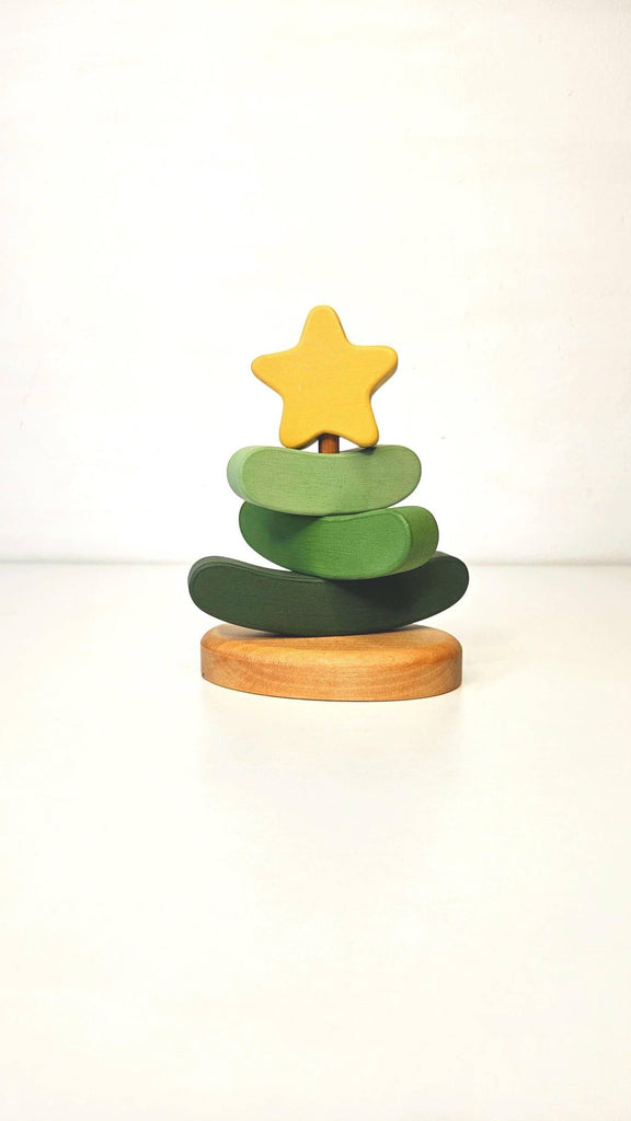 The Handmade Wooden Stacking Toy Green Christmas Tree features green curved layers and a yellow star on a rounded wooden base, shown against a white background. Eco-friendly and minimalist, it's perfect for mindful play.