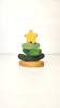 The Handmade Wooden Stacking Toy Green Christmas Tree features green curved layers and a yellow star on a rounded wooden base, shown against a white background. Eco-friendly and minimalist, it's perfect for mindful play.