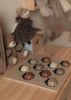 The My Little Lady Bug Wooden Puzzle, featuring ladybug-shaped pieces, sits on a wooden table surrounded by plush toys—including a teddy bear and a doll in a brown dress—in a cozy, softly lit children’s room, offering a charming example of Montessori-inspired toys that encourage hands-on learning and play.